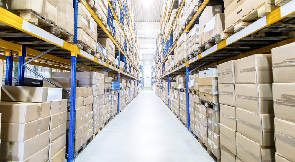 Rows of shelves with cardboard boxes in large distribution warehouse